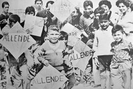 Black and white photograph of children holding kites which say Allende